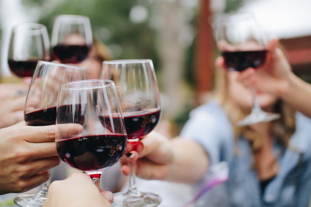 Friends raising glasses of red wine at a sunlit table