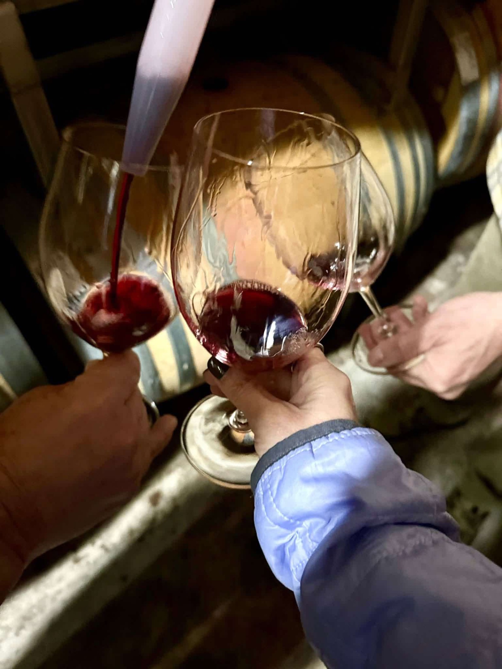 Two glasses of red wine clinking over a barrel